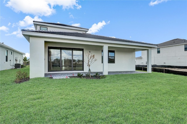 rear view of house featuring central AC unit and a yard