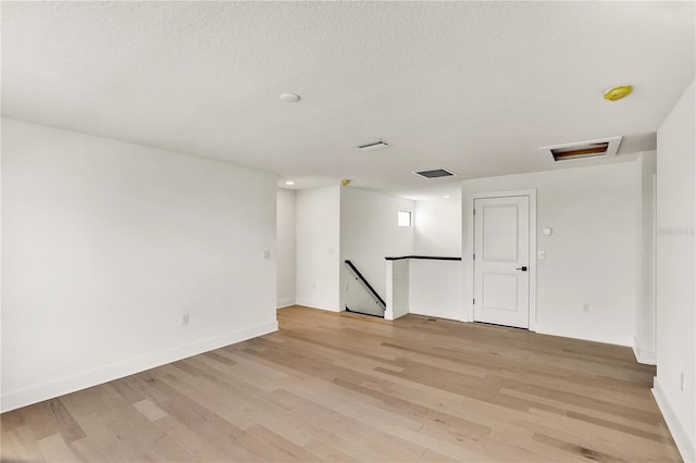 unfurnished room featuring light wood-type flooring and a textured ceiling