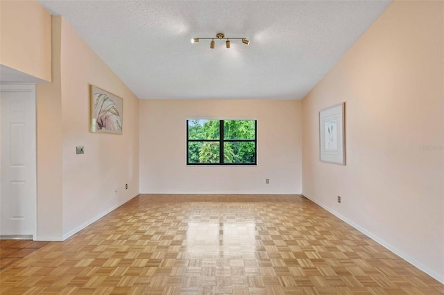 unfurnished room with vaulted ceiling, a textured ceiling, and light parquet flooring