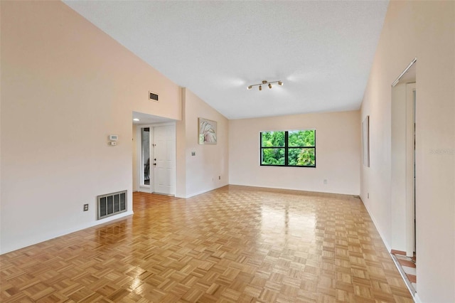 empty room with a textured ceiling, light parquet flooring, and high vaulted ceiling