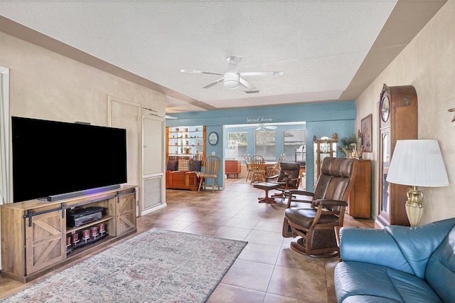 living room with tile patterned flooring, a textured ceiling, and ceiling fan