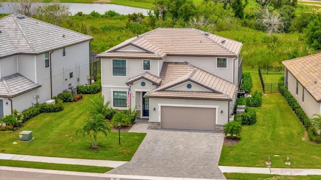 view of front of home with a garage, a water view, and a front lawn