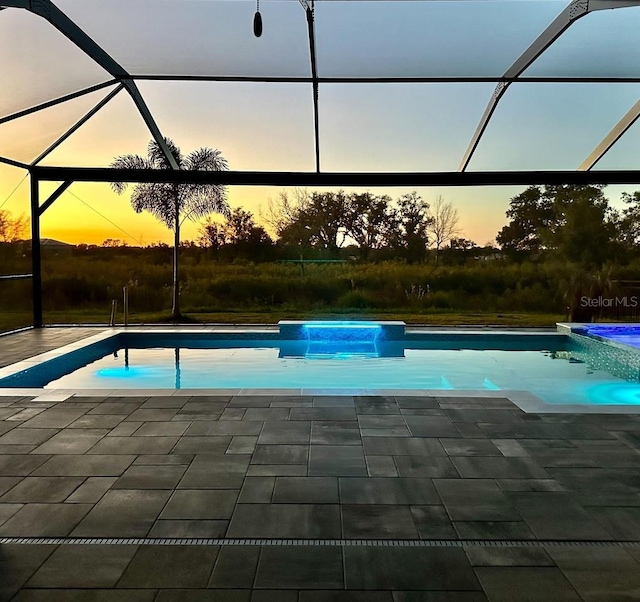 pool at dusk with a lanai and a patio area