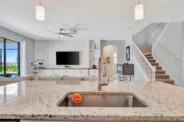 kitchen featuring sink, decorative light fixtures, light stone countertops, and ceiling fan