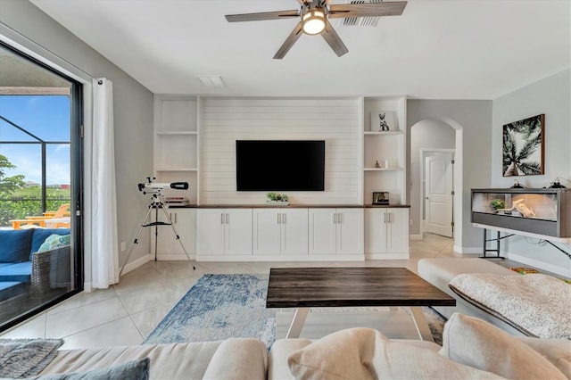 living room featuring built in shelves, ceiling fan, and light tile patterned floors