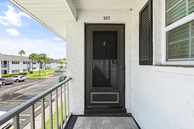 entrance to property with a balcony, uncovered parking, and stucco siding