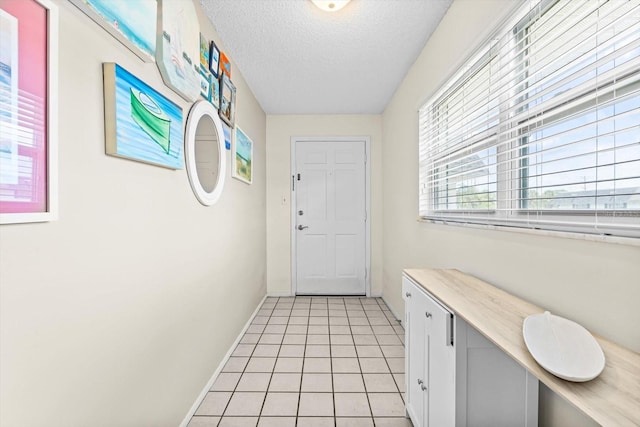 doorway to outside with a textured ceiling and light tile patterned floors