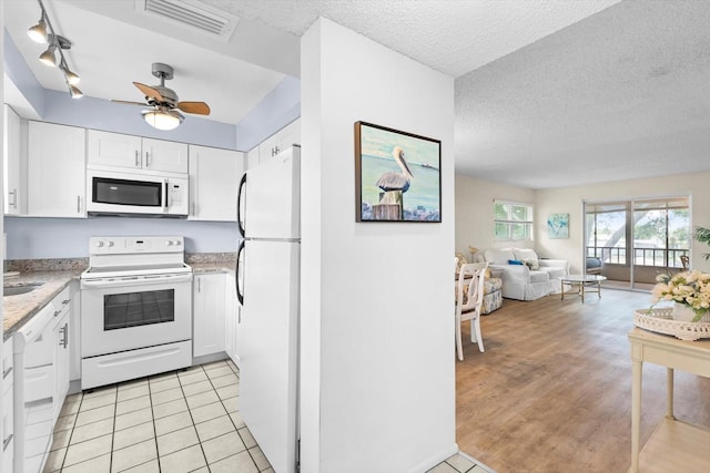 kitchen featuring visible vents, open floor plan, white cabinets, a textured ceiling, and white appliances