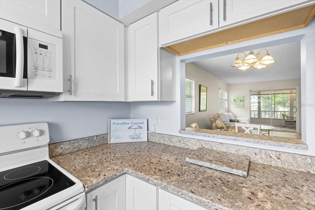 kitchen with white appliances, white cabinetry, and light stone counters