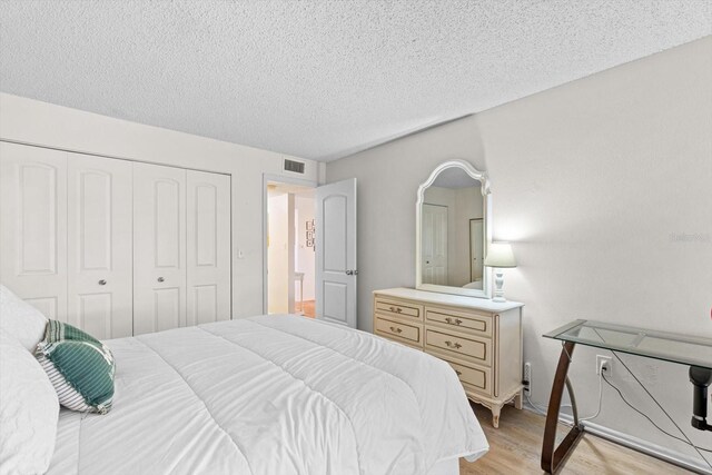 bedroom featuring a closet, a textured ceiling, and light wood-type flooring