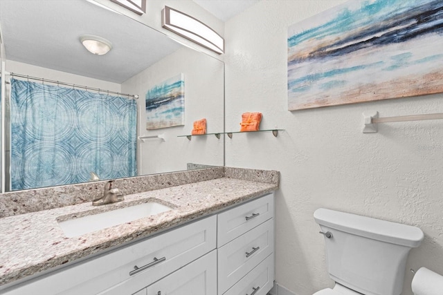 full bathroom with toilet, a textured wall, and vanity