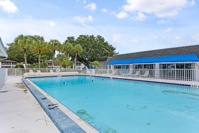 pool with a patio area and fence