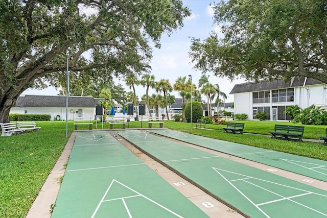 view of community with a lawn and shuffleboard