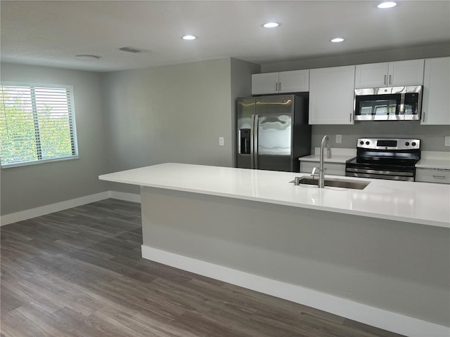 kitchen with appliances with stainless steel finishes, sink, white cabinetry, and dark wood-type flooring