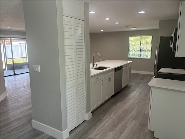 kitchen with appliances with stainless steel finishes, sink, white cabinets, and wood-type flooring