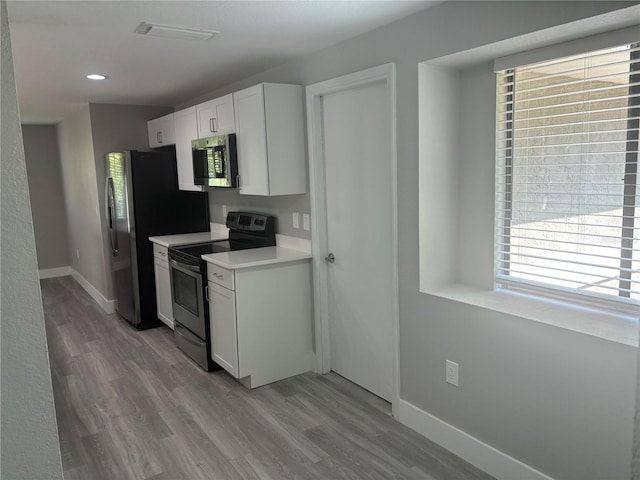 kitchen featuring appliances with stainless steel finishes, a healthy amount of sunlight, light hardwood / wood-style floors, and white cabinetry