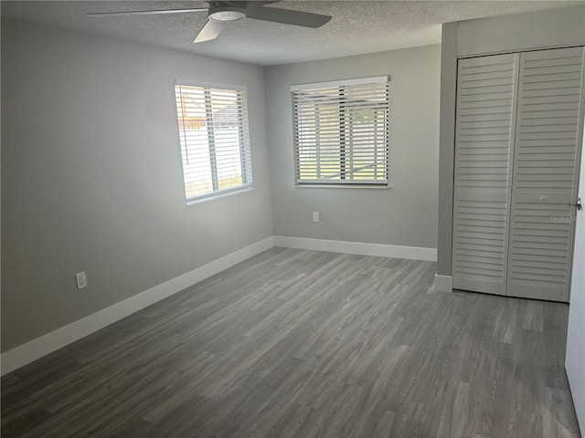 unfurnished bedroom with a textured ceiling, a closet, hardwood / wood-style floors, and ceiling fan