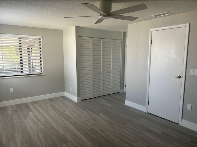 unfurnished bedroom featuring ceiling fan, a closet, dark hardwood / wood-style flooring, and a textured ceiling