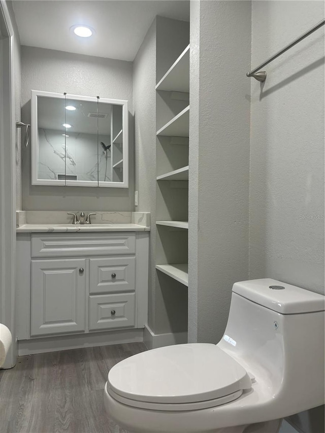 bathroom with hardwood / wood-style floors, vanity, and toilet