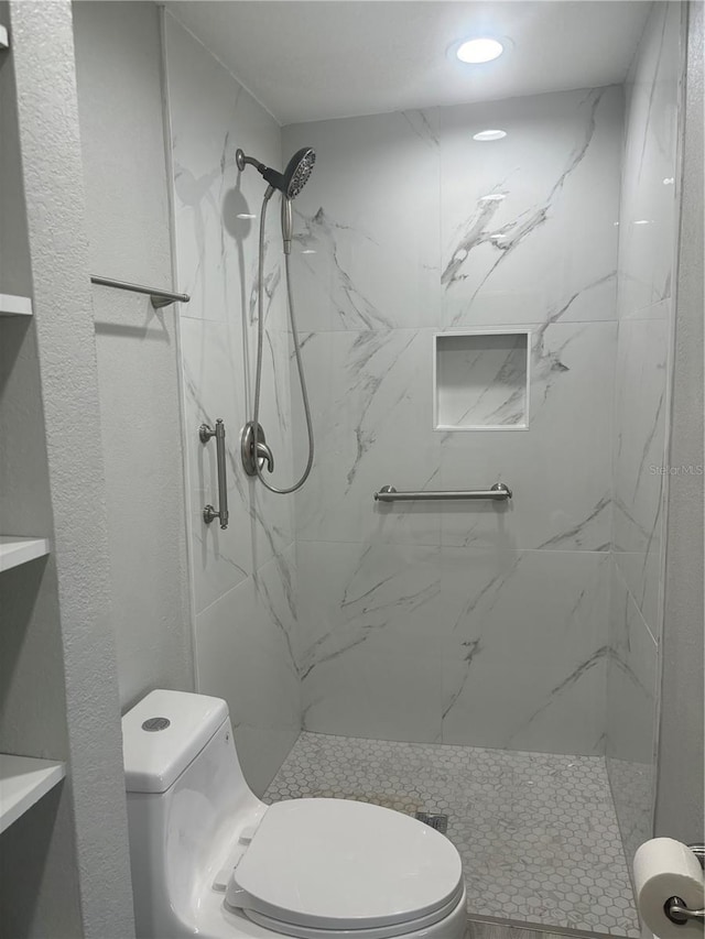 bathroom featuring a tile shower and toilet