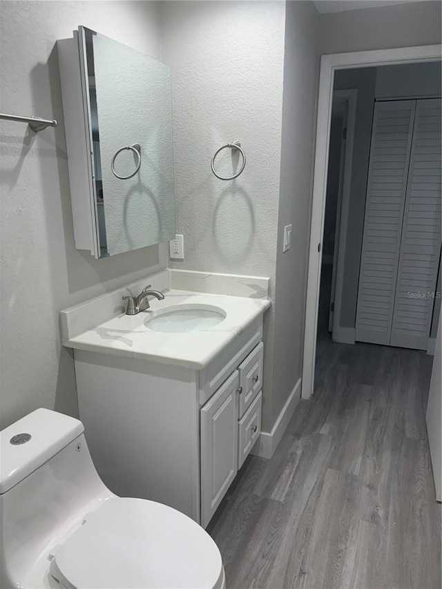 bathroom featuring toilet, vanity, and hardwood / wood-style floors