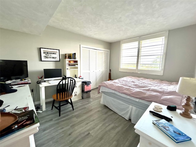 bedroom with a textured ceiling, hardwood / wood-style floors, and a closet