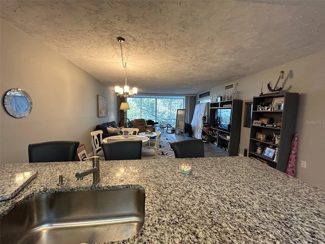 kitchen with a textured ceiling, sink, and stone counters