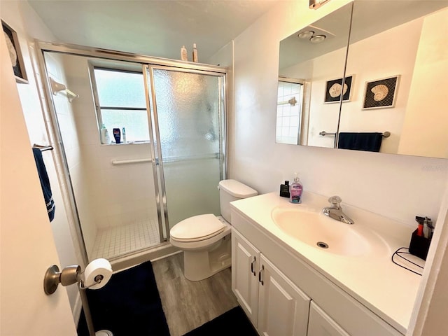 bathroom featuring vanity, toilet, wood-type flooring, and a shower with door