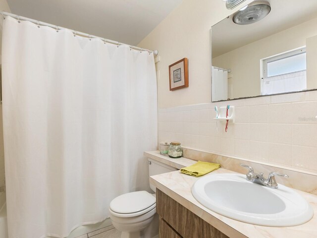 bathroom with vanity, toilet, tasteful backsplash, and tile walls