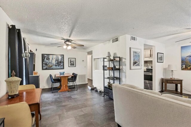 living room with ceiling fan and a textured ceiling