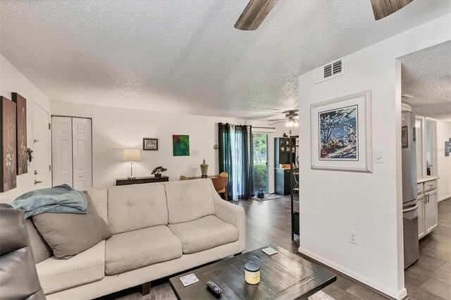 living room featuring a textured ceiling, dark hardwood / wood-style floors, and ceiling fan