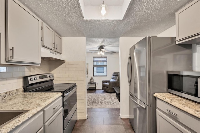 kitchen featuring light stone countertops, white cabinets, dark tile patterned flooring, and appliances with stainless steel finishes