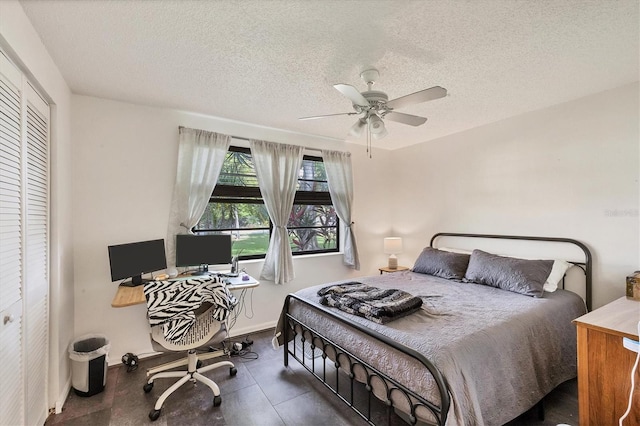 bedroom featuring ceiling fan, a closet, dark tile patterned floors, and a textured ceiling