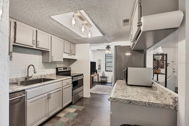 kitchen featuring gray cabinetry, sink, ceiling fan, decorative backsplash, and appliances with stainless steel finishes