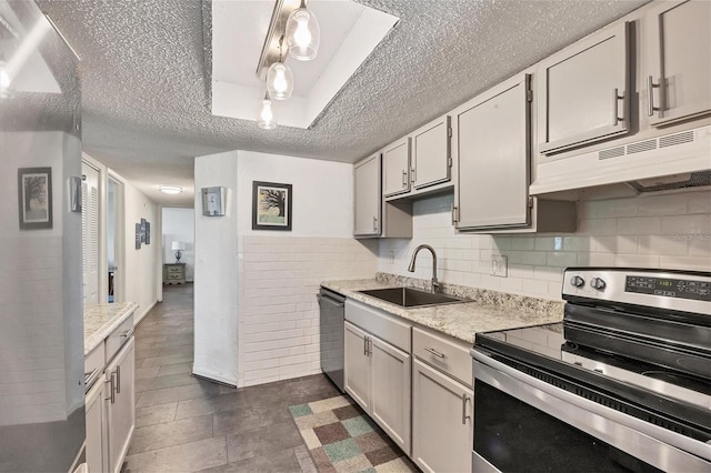 kitchen with pendant lighting, sink, appliances with stainless steel finishes, light stone countertops, and a textured ceiling