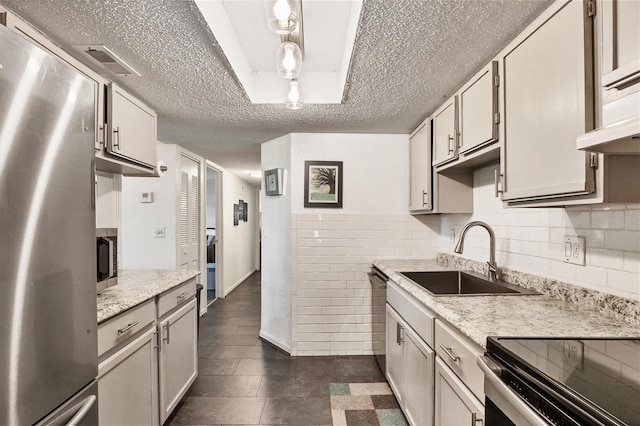 kitchen featuring white cabinetry, sink, light stone counters, stainless steel appliances, and a textured ceiling