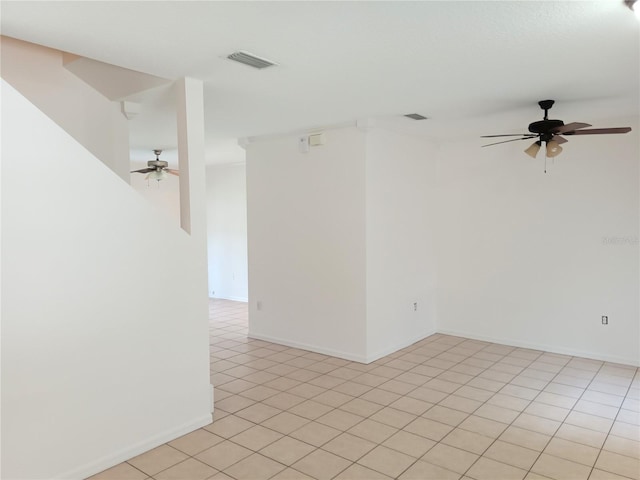 spare room with a ceiling fan, visible vents, and baseboards