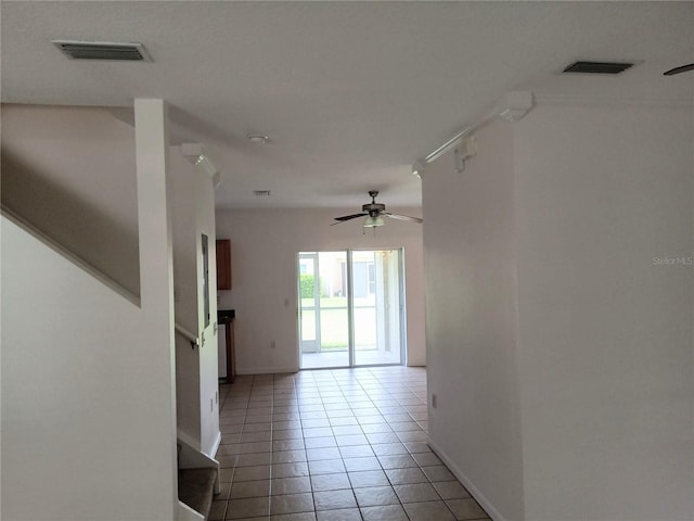 hall featuring light tile patterned floors, visible vents, baseboards, and stairs