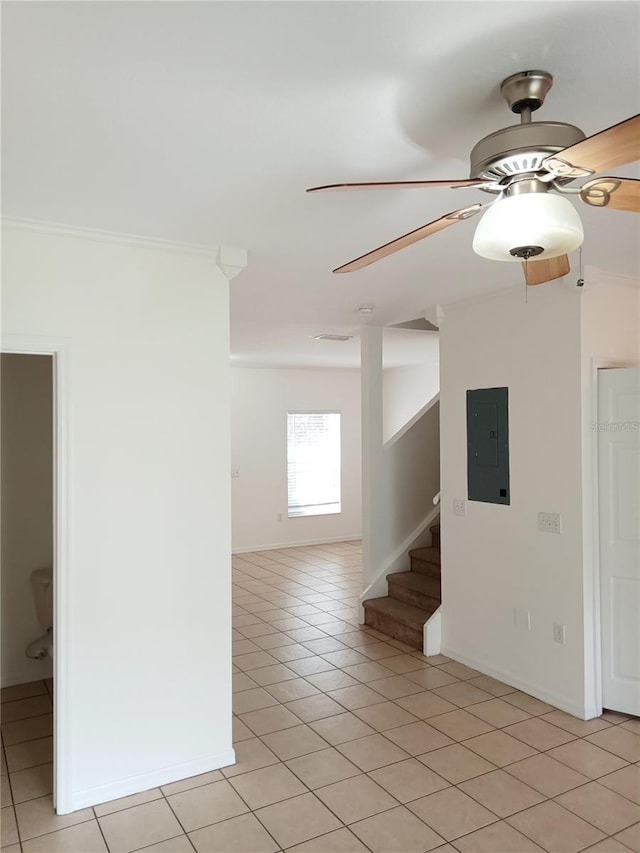 spare room featuring electric panel, light tile patterned flooring, ceiling fan, and stairs