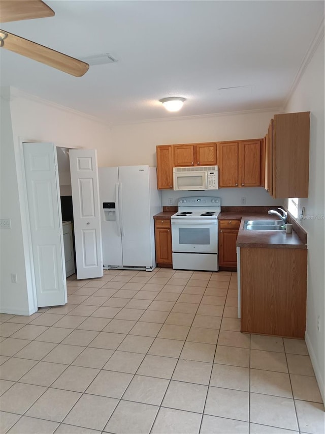 kitchen with white appliances, ornamental molding, dark countertops, and a sink