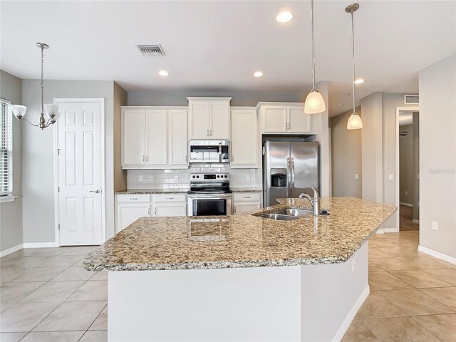 kitchen with a center island with sink, tasteful backsplash, stainless steel appliances, light tile patterned floors, and sink