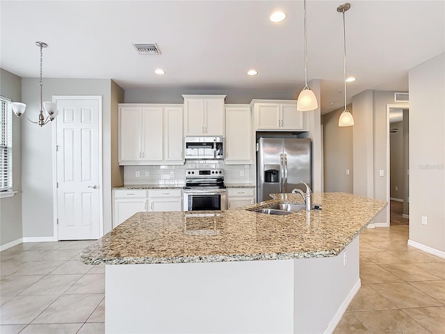 kitchen with stainless steel appliances, tasteful backsplash, visible vents, a sink, and an island with sink