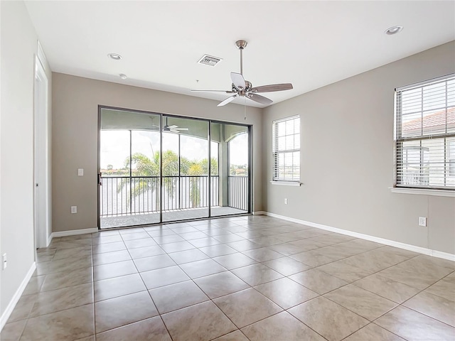 empty room featuring baseboards, visible vents, a ceiling fan, and light tile patterned flooring