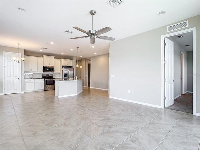 unfurnished living room featuring ceiling fan with notable chandelier and light tile patterned floors