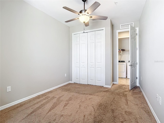 unfurnished bedroom featuring light carpet, a closet, ceiling fan, and independent washer and dryer