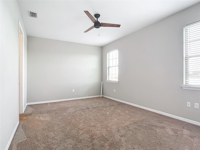 empty room featuring carpet, plenty of natural light, visible vents, and baseboards