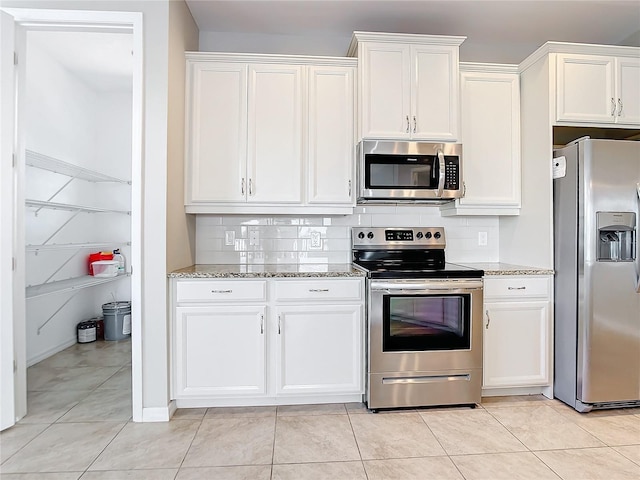 kitchen featuring appliances with stainless steel finishes, white cabinets, backsplash, and light stone countertops