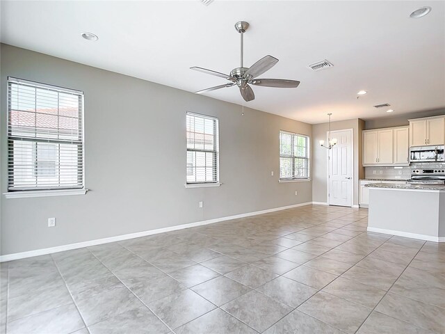 unfurnished living room featuring ceiling fan with notable chandelier and light tile patterned floors