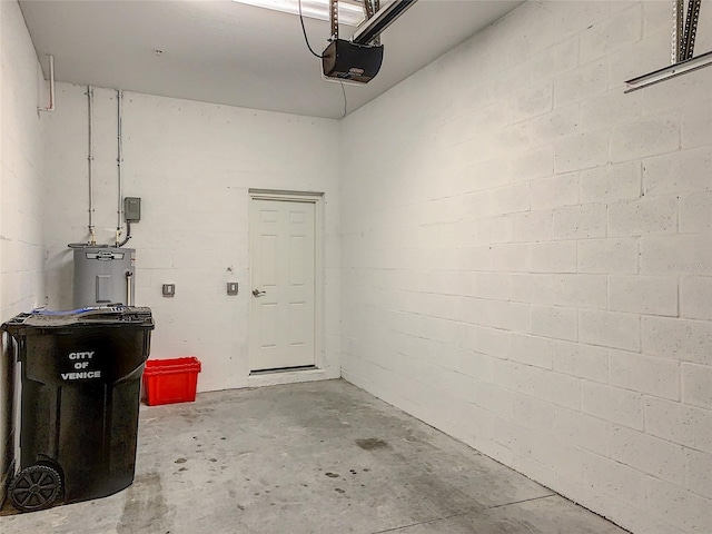 garage featuring concrete block wall, a garage door opener, and electric water heater