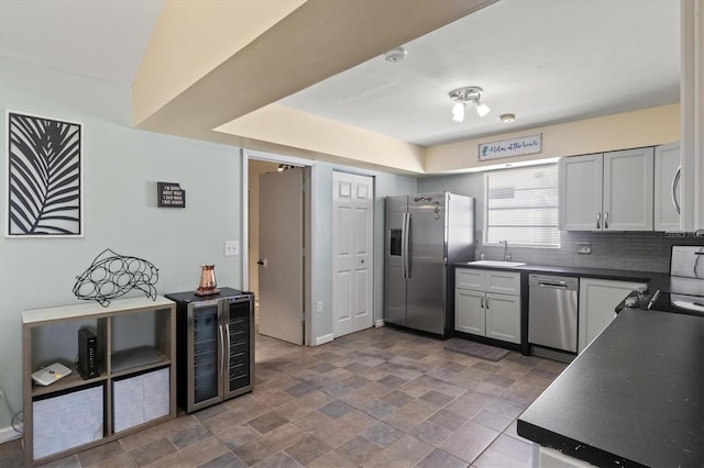 kitchen with dark tile patterned flooring, sink, stainless steel appliances, and backsplash